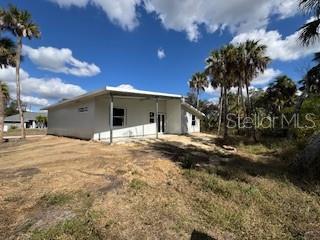 A white, single-story house with a covered patio stands on a dry, grassy lot — 16411 BAUERS AVENUE, PORT CHARLOTTE, FL