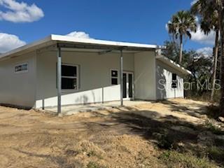A modern, single-story house with a metal-framed porch stands on a sandy, undeveloped lot — 16411 BAUERS AVENUE, PORT CHARLOTTE, FL