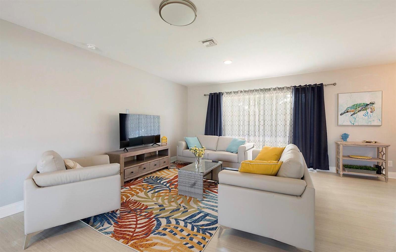 A living room features light-colored sofas, a patterned area rug, and a television console — 2740 SE 1st Court, Pompano Beach FL 33062, POMPANO BEACH, FL