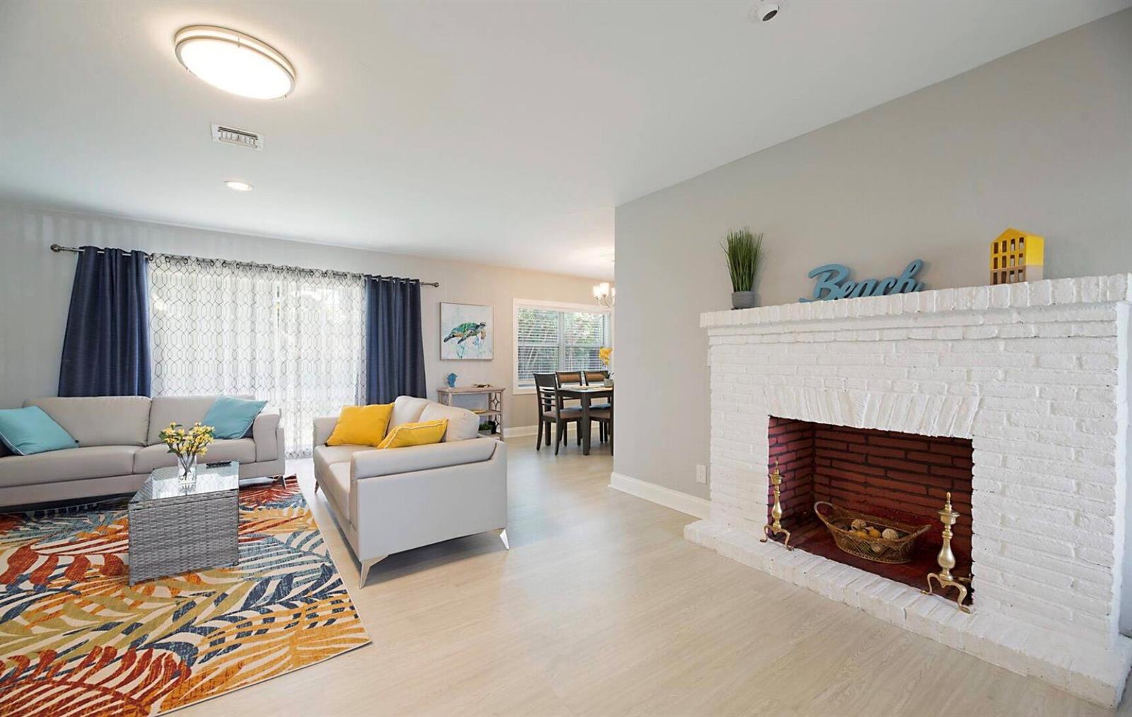 A living room features a white brick fireplace, light wood flooring, and two gray sofas — 2740 SE 1st Court, Pompano Beach FL 33062, POMPANO BEACH, FL