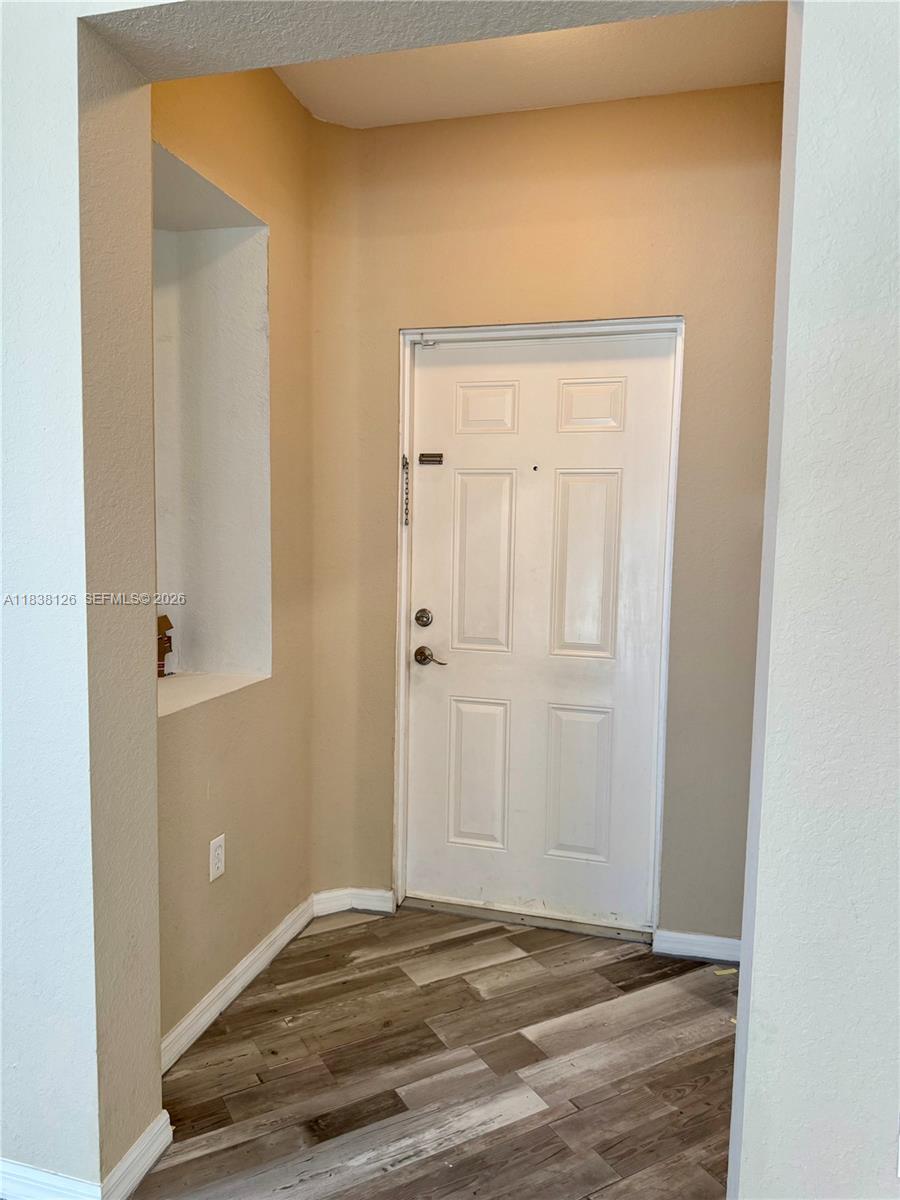 An entryway features a white door, light-colored walls, and wood-look flooring — 8800 NW 107th Ct # 202, Doral FL 33178, DORAL, FL