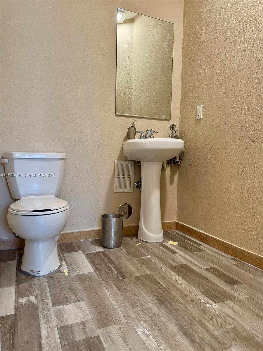 A bathroom features a white pedestal sink, a toilet, and wood-look tile flooring — 8800 NW 107th Ct # 202, Doral FL 33178, DORAL, FL