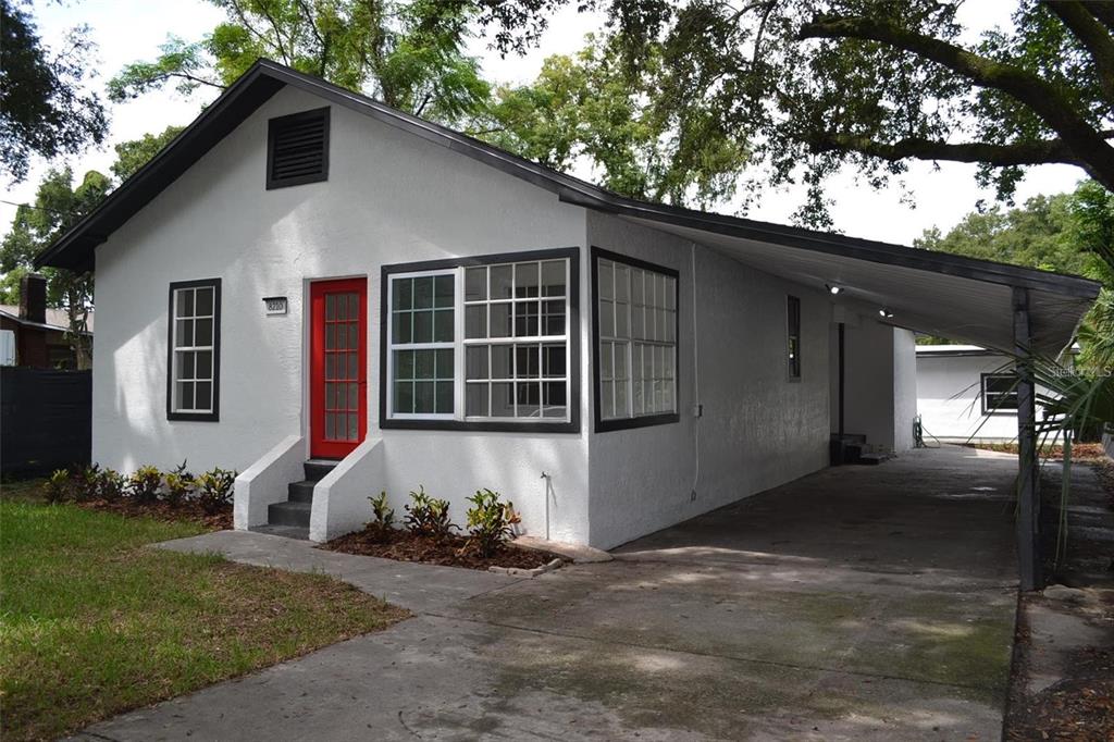 A white house with a red front door and an attached carport — 8210 N KLONDYKE STREET, TAMPA, FL