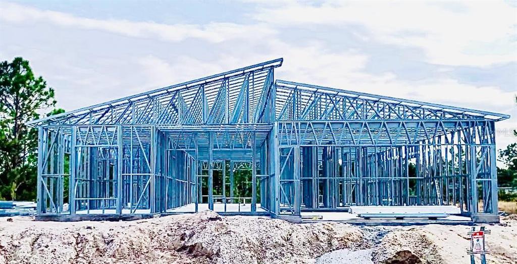 The exterior of a house under construction features a metal framing structure on a dirt lot — 54 EVERGREEN STREET, PUNTA GORDA, FL
