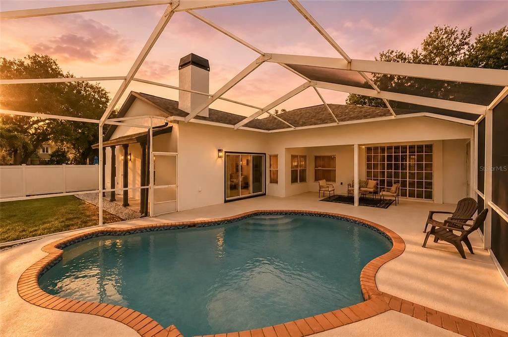 A backyard swimming pool with a brick border sits inside a screened-in patio enclosure — 9238 SEA OAKS COURT, SEMINOLE, FL