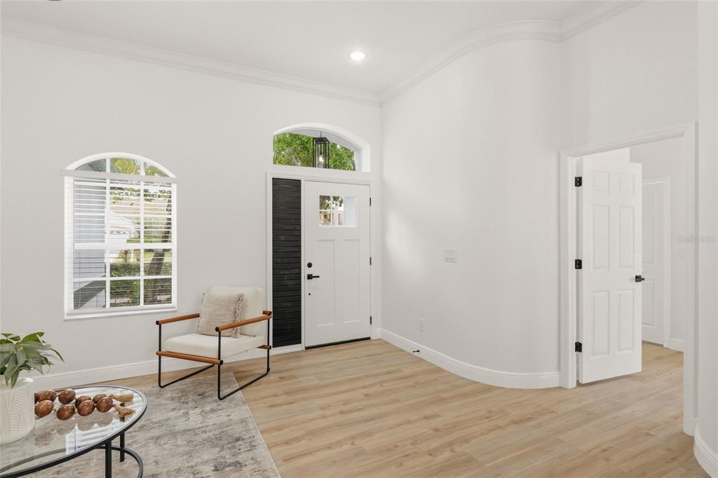 An entryway features light wood flooring, a white front door, and a curved wall — 9238 SEA OAKS COURT, SEMINOLE, FL