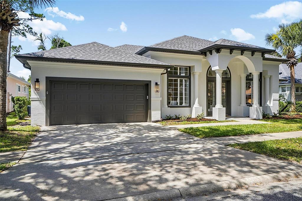 A single-story house with a white stucco exterior, dark garage door, and arched entryway — 21 EASTLAKE DRIVE, PALM COAST, FL
