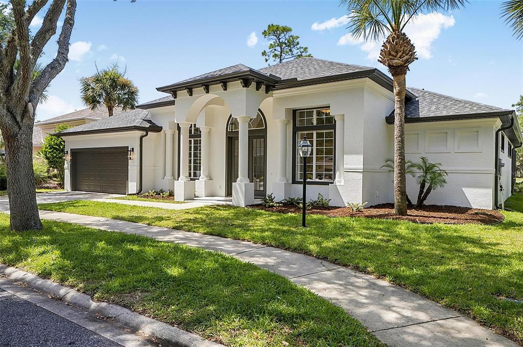 A white single-story house with a dark roof, arched entryway, and a two-car garage — 21 EASTLAKE DRIVE, PALM COAST, FL