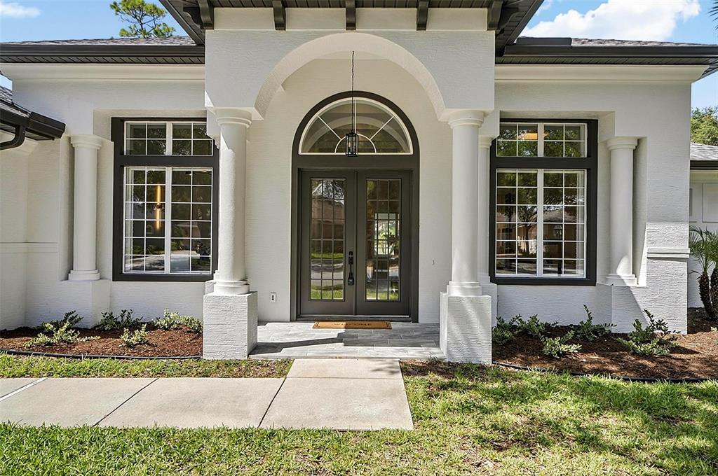 The exterior of a white house features a covered entryway with columns and double doors — 21 EASTLAKE DRIVE, PALM COAST, FL