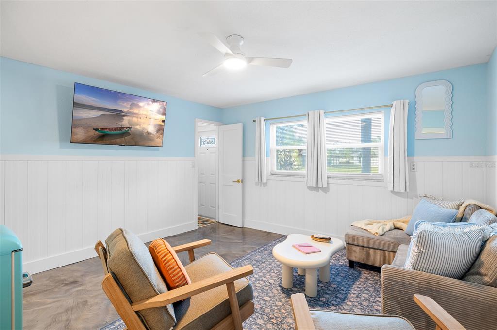 A living room features light blue walls, white wainscoting, a ceiling fan, and gray furniture — 727 47TH STREET W, PALMETTO, FL