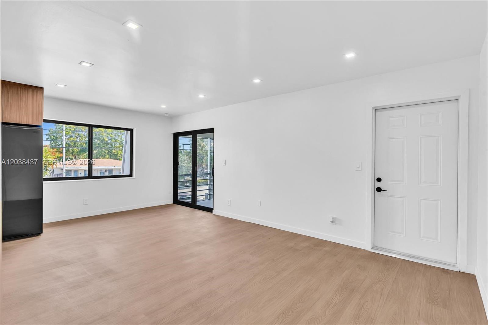 An empty room features light wood-look flooring, white walls, recessed lighting, and a white door — 1924 NE 26th St # 4, Wilton Manors FL 33305, WILTON MANORS, FL