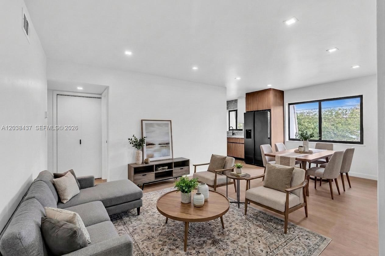 A modern open-concept living and dining area features light wood floors and white walls — 1924 NE 26th St # 4, Wilton Manors FL 33305, WILTON MANORS, FL