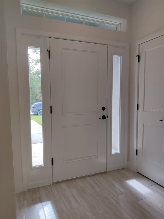 A white front door with side lights and a transom window opens into a tiled entryway — 14606 MOCKING WREN ROAD, WEEKI WACHEE, FL