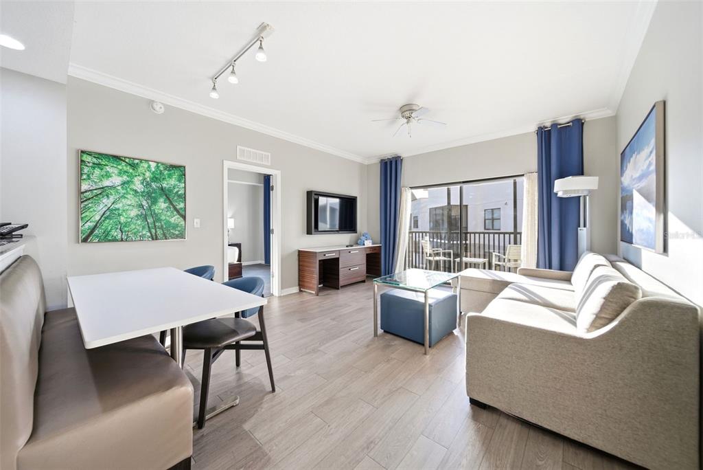A living room features a dining area, a sofa, a television, and a balcony view — 14051 GROVE RESORT AVENUE UNIT 1705, WINTER GARDEN, FL