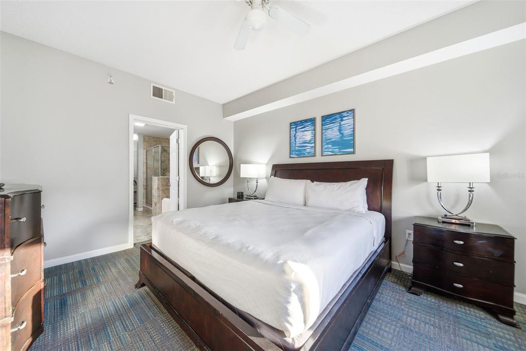 A bedroom features a dark wood bed frame, two nightstands, and blue patterned carpeting — 14051 GROVE RESORT AVENUE UNIT 1705, WINTER GARDEN, FL