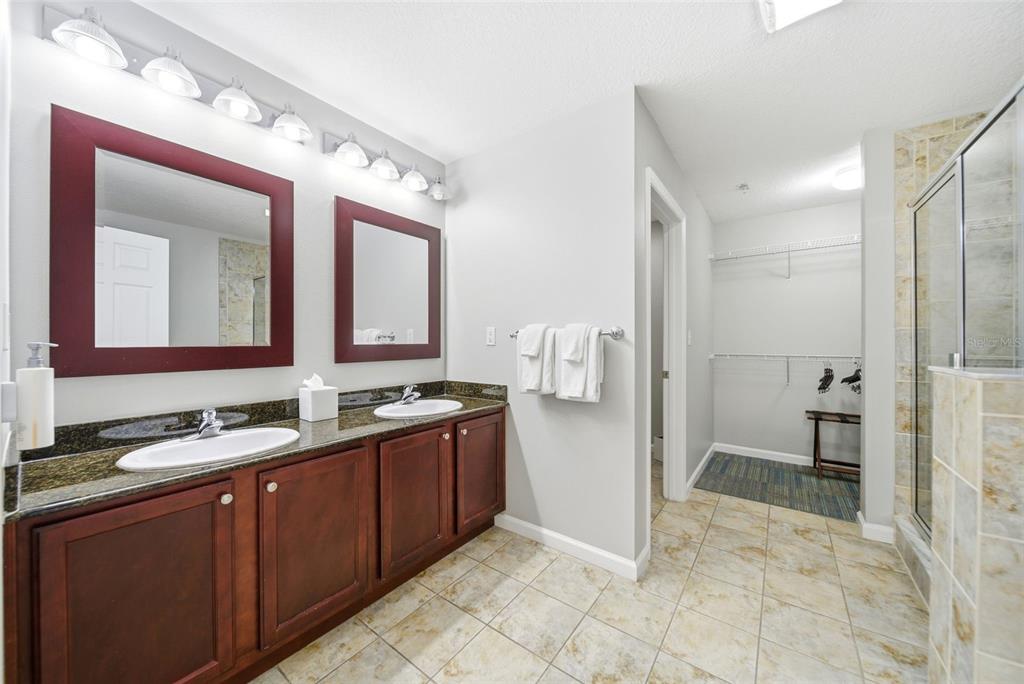 A bathroom features a double vanity with dark wood cabinets, granite countertops, and a walk-in closet — 14051 GROVE RESORT AVENUE UNIT 1705, WINTER GARDEN, FL