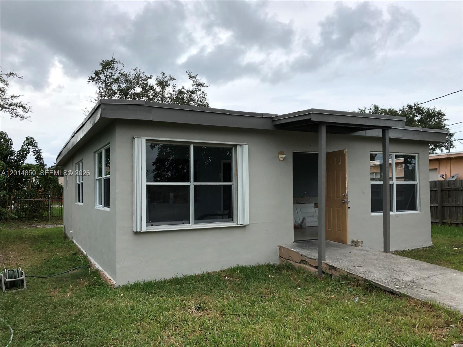 A single-story gray house with a flat roof, a small front porch, and grass yard — 424 SW 12th Ave, Homestead FL 33030, HOMESTEAD, FL