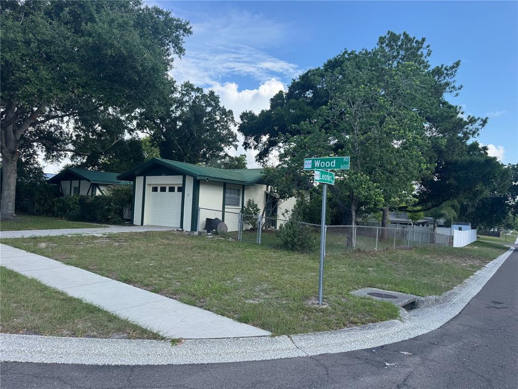 A single-story house with a green roof sits on a corner lot with street signs — 624 WOOD ROAD, SEFFNER, FL