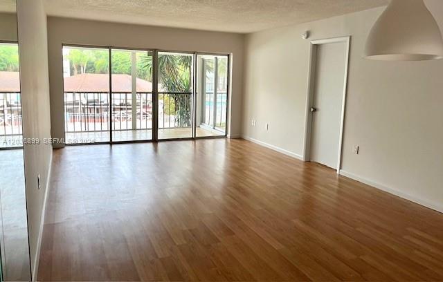 An empty living room features light wood flooring, a white ceiling, and large sliding glass doors — 3920 Inverrary Blvd # 204C, Lauderhill FL 33319, LAUDERHILL, FL