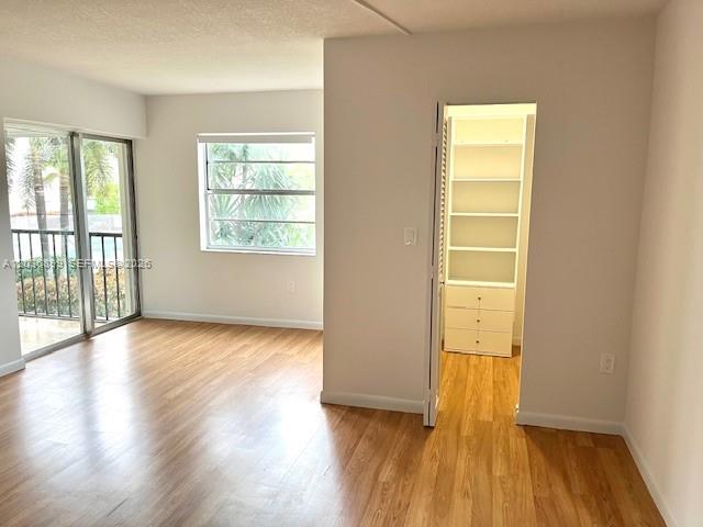 A room with wood-look flooring, a window, a sliding glass door, and an open closet — 3920 Inverrary Blvd # 204C, Lauderhill FL 33319, LAUDERHILL, FL