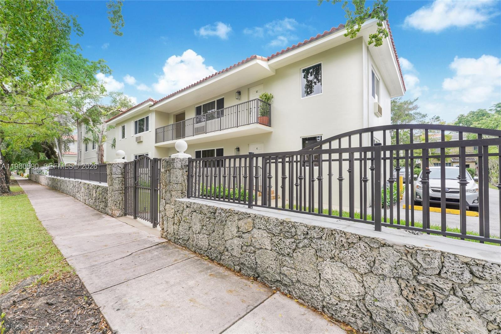 A two-story apartment building features a stone wall, metal fence, and a second-floor balcony — 35 Antilla Ave, Coral Gables FL 33134, CORAL GABLES, FL