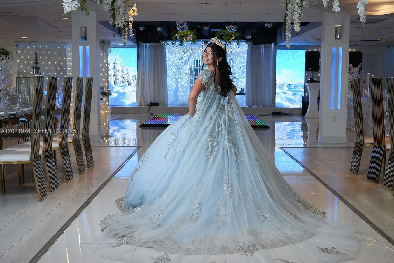 A young woman in a formal blue gown stands in a decorated event hall — 8250 SW flagler, Miami FL 33144, MIAMI, FL