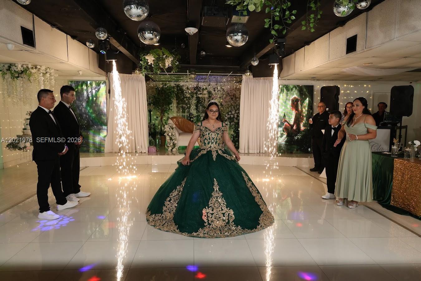 A young woman in a green gown stands on a dance floor with indoor pyrotechnics — 8250 SW flagler, Miami FL 33144, MIAMI, FL