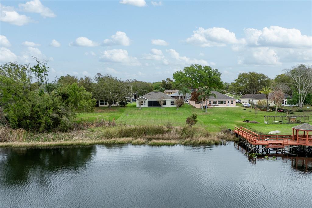 An aerial view of a waterfront backyard with a wooden dock and several houses — 3804 BAYSHORE CIRCLE, TAVARES, FL