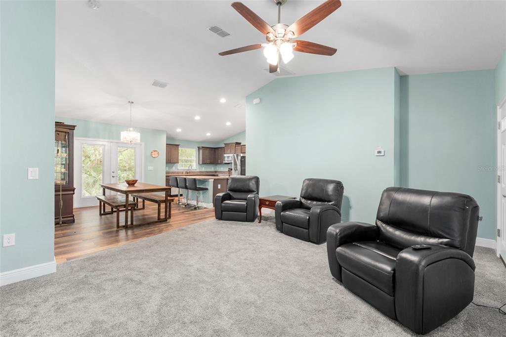 A living room with light blue walls, gray carpeting, and three black leather recliners — 6144 AVENUE G, MC INTOSH, FL