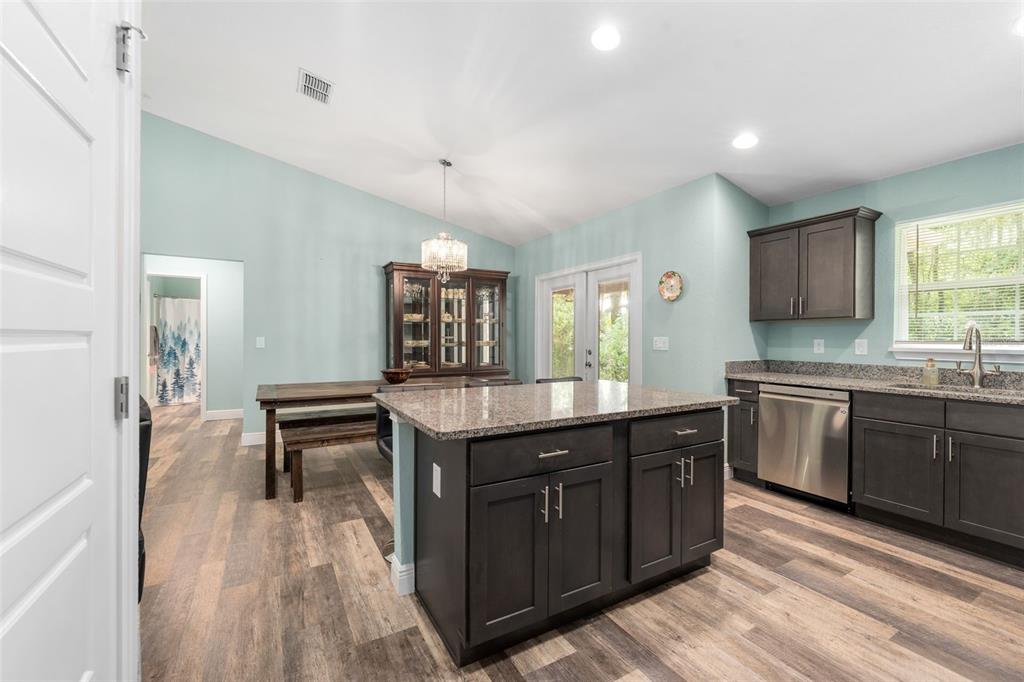 A kitchen features dark cabinets, a granite-topped island, and light blue walls — 6144 AVENUE G, MC INTOSH, FL