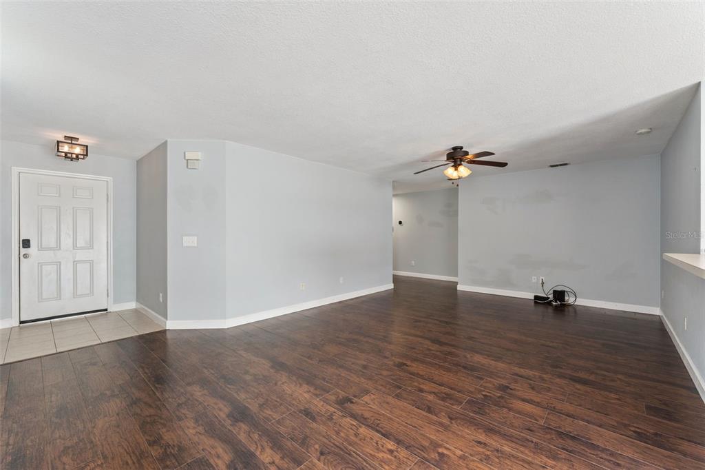 An open living area features light gray walls, dark wood-look flooring, and a ceiling fan — 825 CLIFTON HILLS STREET, ORLANDO, FL
