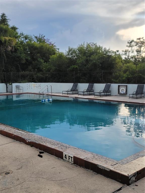 A rectangular swimming pool with a four-foot depth marker sits in front of lounge chairs — 2430 LEMON TREE LANE UNIT 2I, ORLANDO, FL
