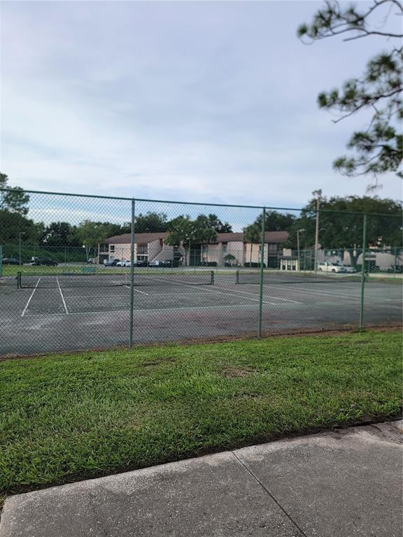A fenced-in tennis court sits in front of a multi-story apartment building — 2430 LEMON TREE LANE UNIT 2I, ORLANDO, FL
