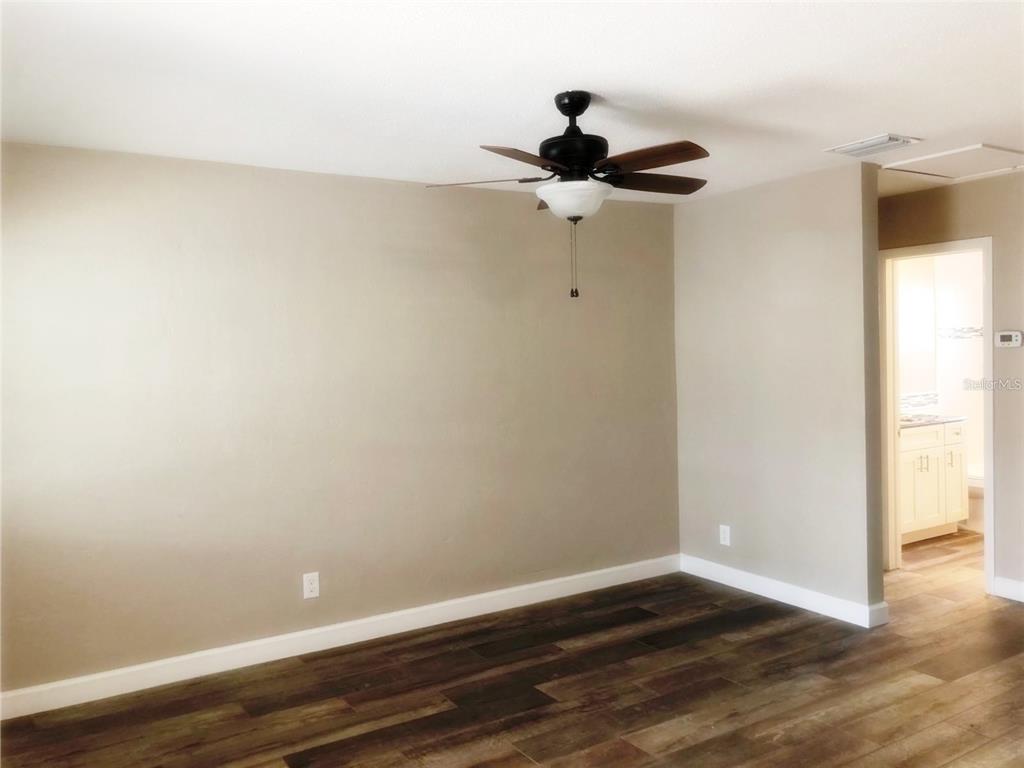 A room with beige walls, a ceiling fan, and dark wood-look flooring — 520 70TH STREET N UNIT 4, ST PETERSBURG, FL