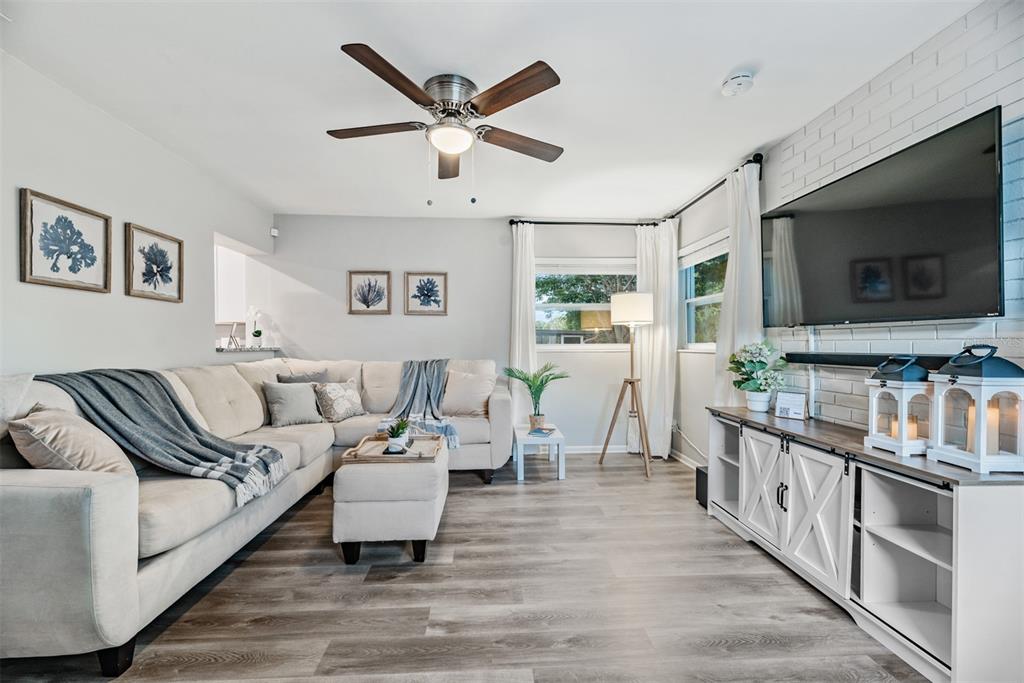 An open-concept kitchen and living area features white cabinetry, stainless steel appliances, and wood flooring — 11354 123RD TERRACE N, LARGO, FL