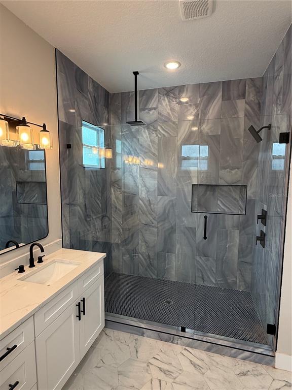 A bathroom features a white vanity, a glass-enclosed shower with gray tile, and marble flooring — 820 46TH AVENUE N, ST PETERSBURG, FL
