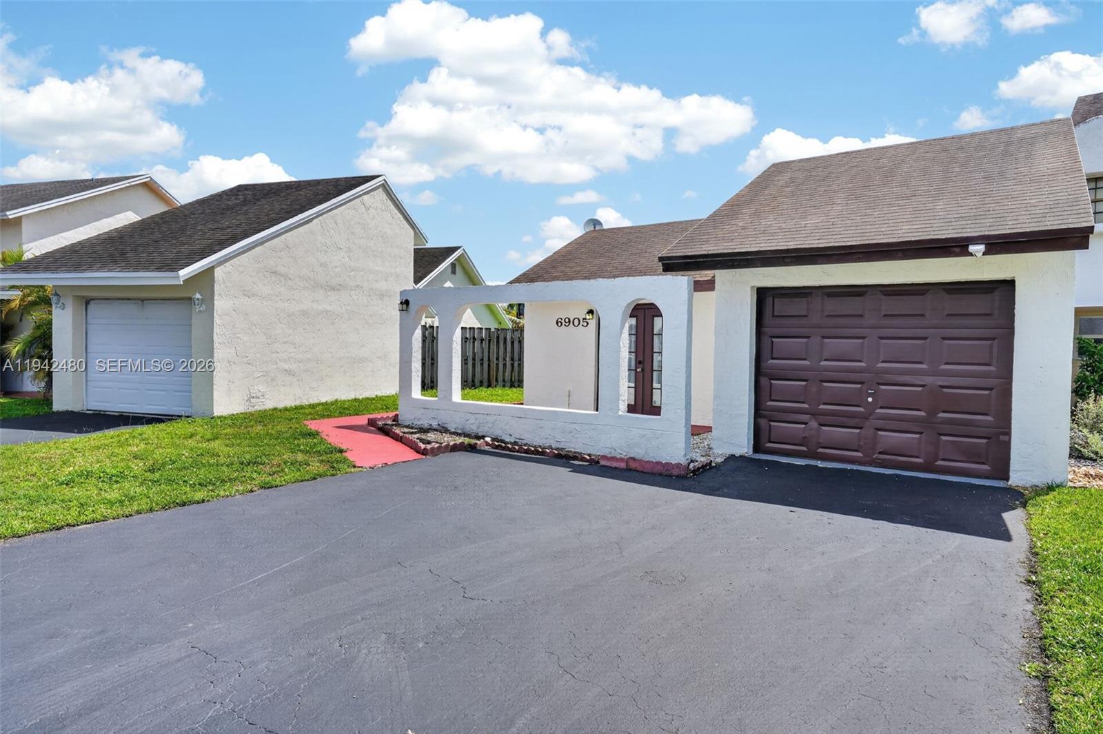 A single-story house with a brown garage door and a white arched privacy wall — 6905 SW 104th Ct, Miami FL 33173, MIAMI, FL