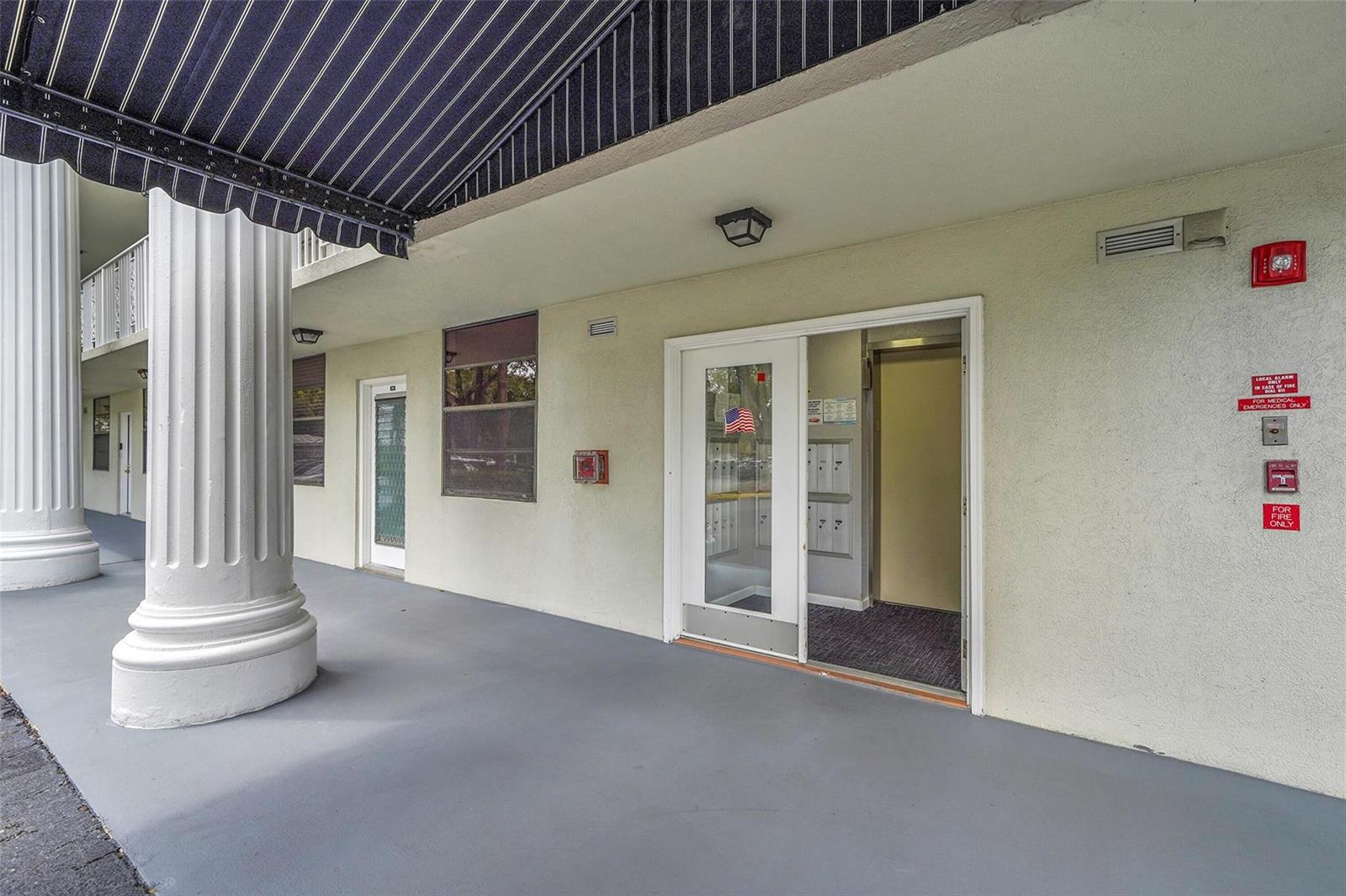 An exterior view of a building entrance with a column, awning, and glass door — 1713 Whitehall Drive # 103, Davie FL 33324, DAVIE, FL