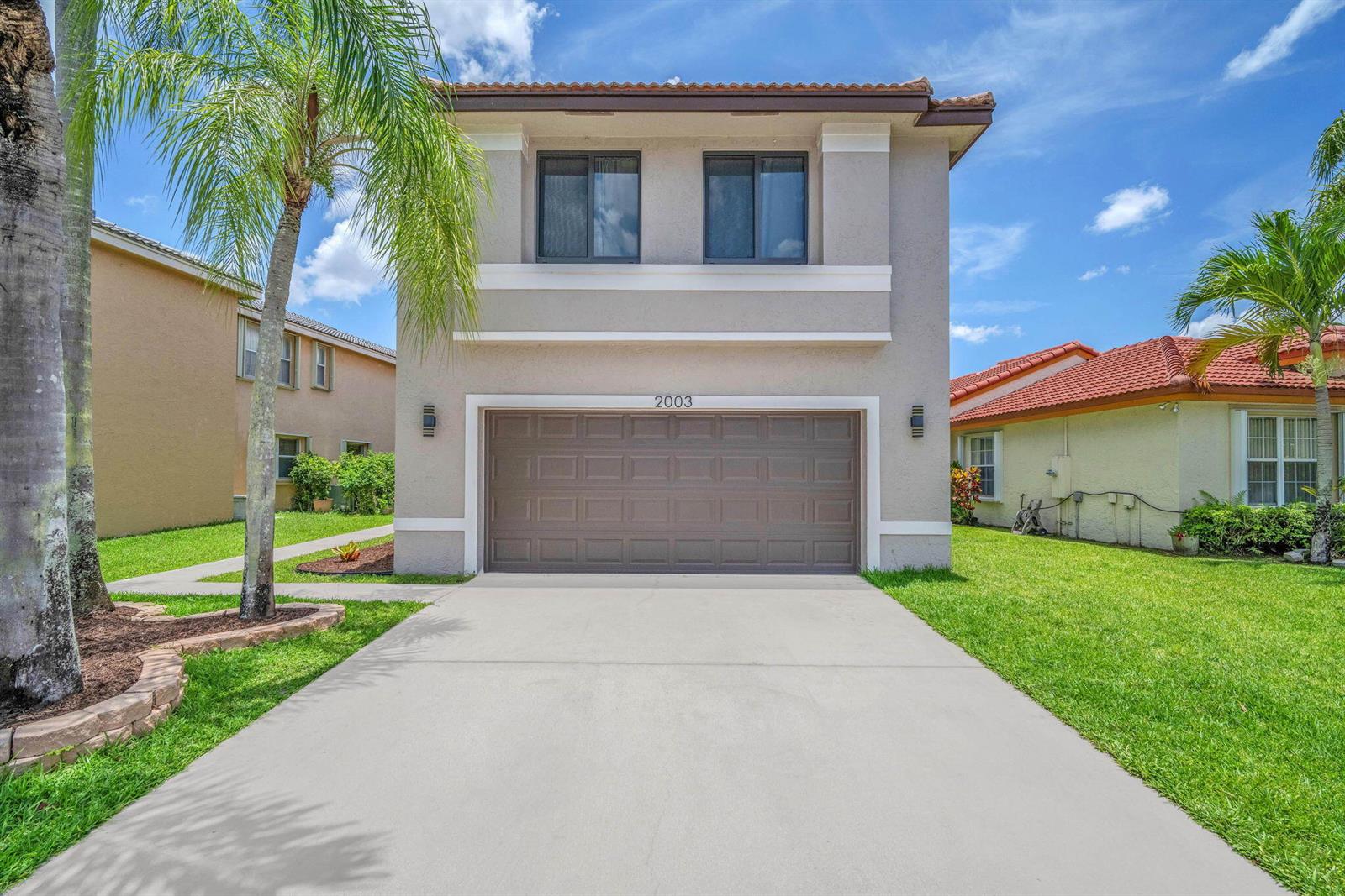 A two-story house with a beige stucco exterior, a two-car garage, and a concrete driveway — 2003 SW 173rd Avenue, Miramar FL 33029, MIRAMAR, FL