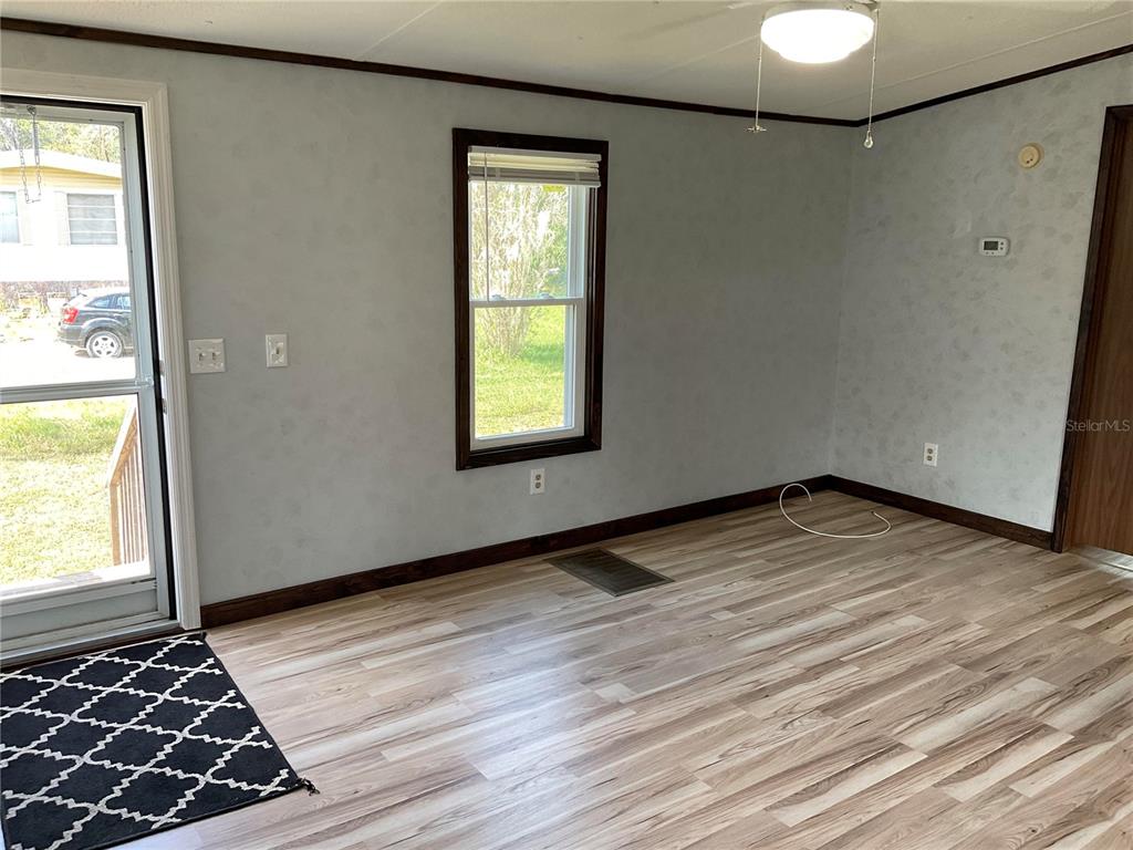 A room with light gray walls, wood-look flooring, a window, and a glass-paneled door — 18057 SE 20TH PLACE, SILVER SPRINGS, FL