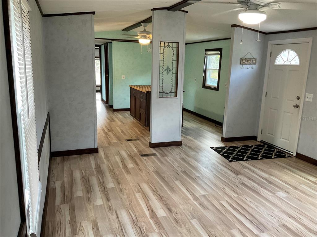 An interior view of a living area with light wood flooring, teal walls, and a doorway — 18057 SE 20TH PLACE, SILVER SPRINGS, FL