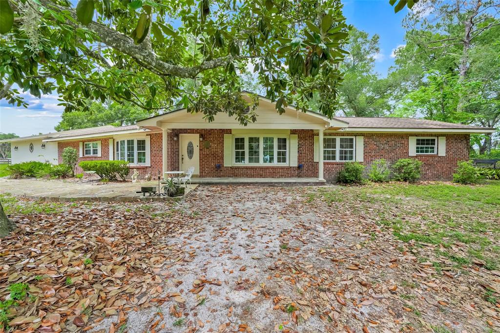 A single-story brick house with a white front door and a large tree in front — 4801 SE HIGHWAY 42, SUMMERFIELD, FL