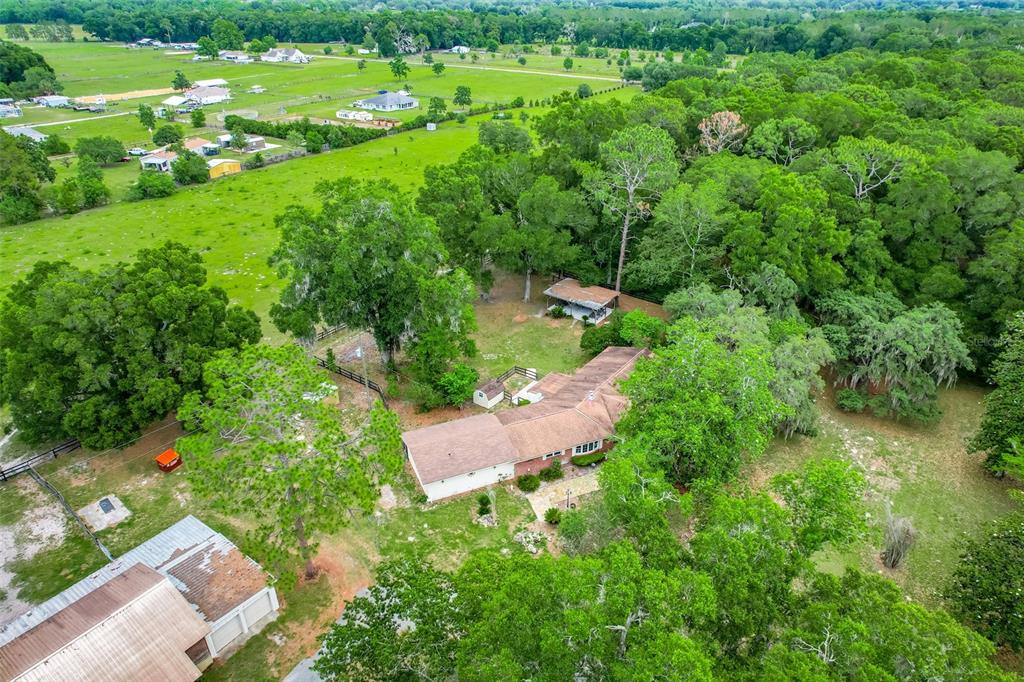 An aerial view shows a house with a brown roof surrounded by trees and pastures — 4801 SE HIGHWAY 42, SUMMERFIELD, FL
