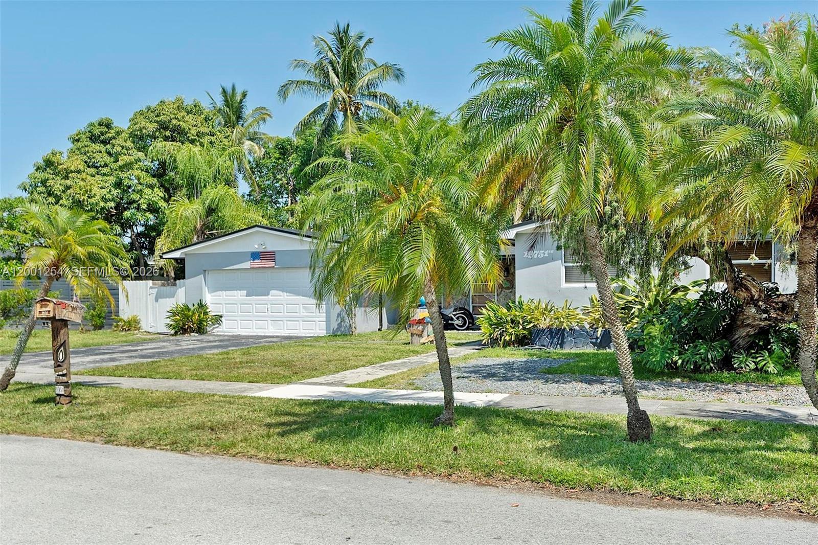A single-story house with a white garage, palm trees, and a lawn under a blue sky — 19751 SW 84th Ave, Cutler Bay FL 33189, CUTLER BAY, FL