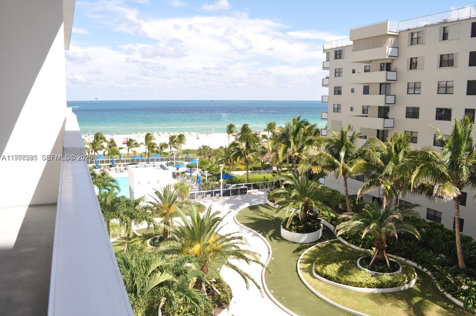 An elevated view shows a beach, ocean, swimming pool, and landscaped grounds from a balcony — 100 Lincoln Rd # 728, Miami Beach FL 33139, MIAMI BEACH, FL