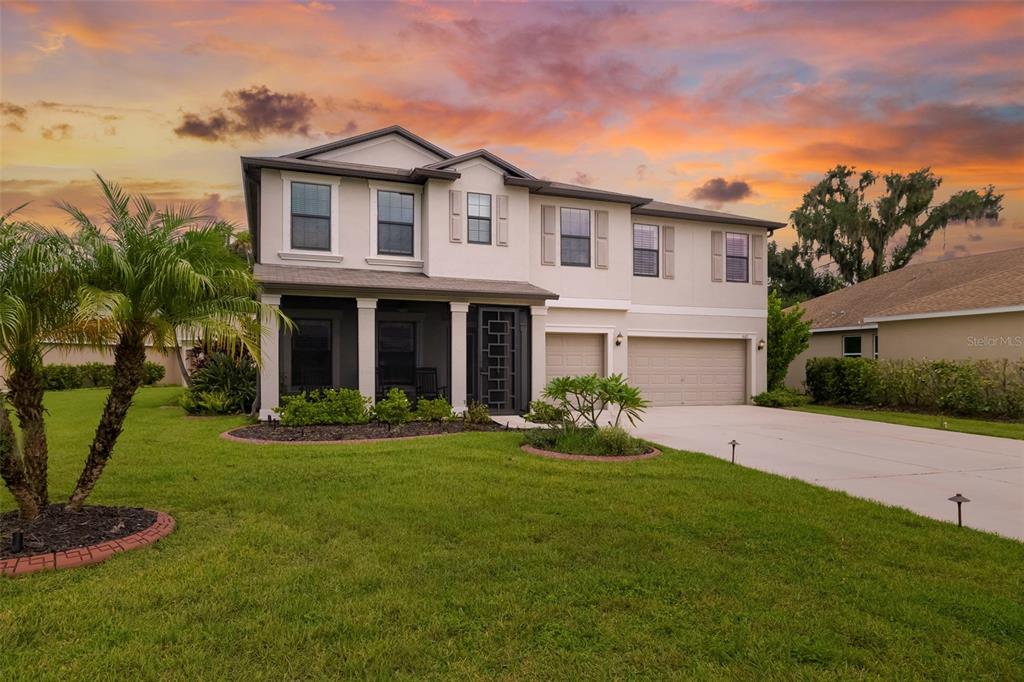 A two-story house with a beige stucco exterior, a three-car garage, and a screened-in porch — 6103 HORSE MILL PLACE, PALMETTO, FL