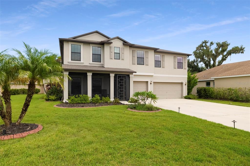 A house exterior features a screened-in front porch with a decorative metal door and garage — 6103 HORSE MILL PLACE, PALMETTO, FL