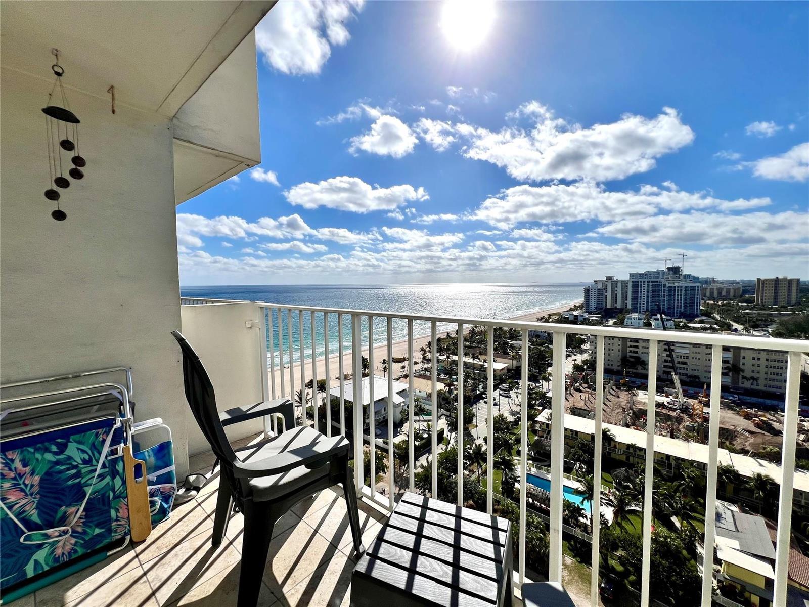 A balcony with a chair and beach gear overlooks the ocean and a coastal city — 111 Briny Avenue # 1908, Pompano Beach FL 33062, POMPANO BEACH, FL