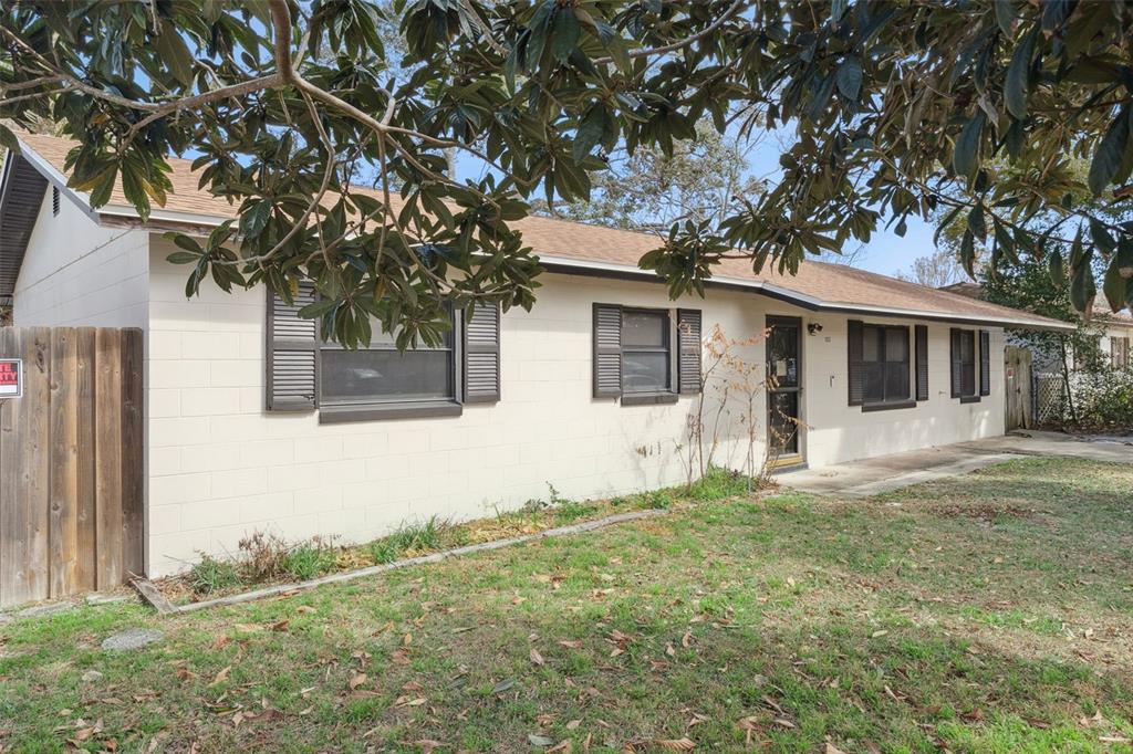 A single-story house with beige concrete block walls, dark shutters, and a brown shingled roof — 1953 LINDA AVENUE, ORMOND BEACH, FL