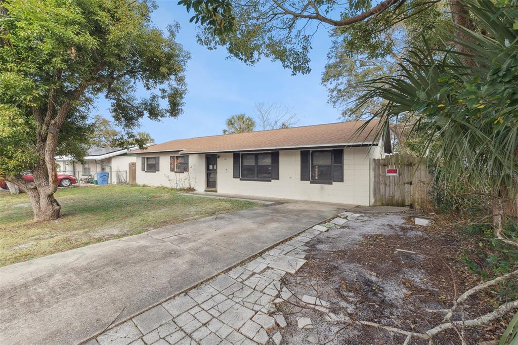 A single-story house with a concrete block exterior, a driveway, and a wooden side gate — 1953 LINDA AVENUE, ORMOND BEACH, FL